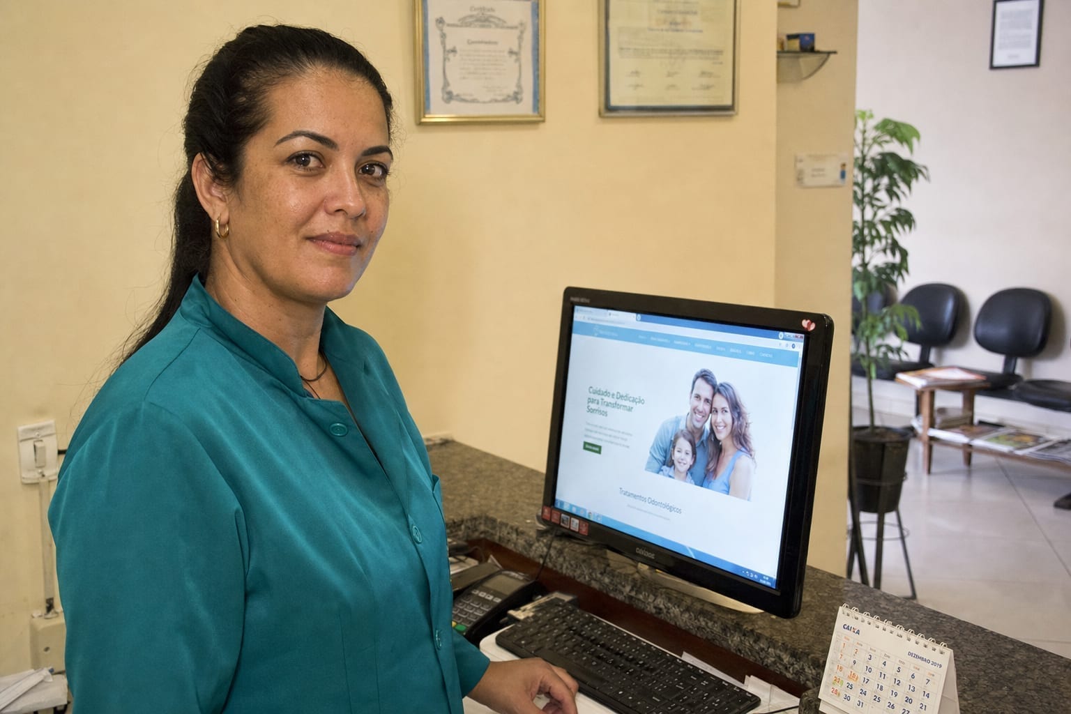 Recepcionista de clínica em BH ao lado do computador exibindo o novo site profissional